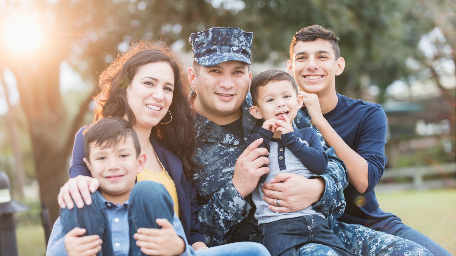 Military family of five smiling together outdoors at sunset
