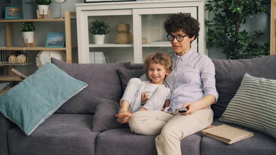 A mom and son on the couch with the remote