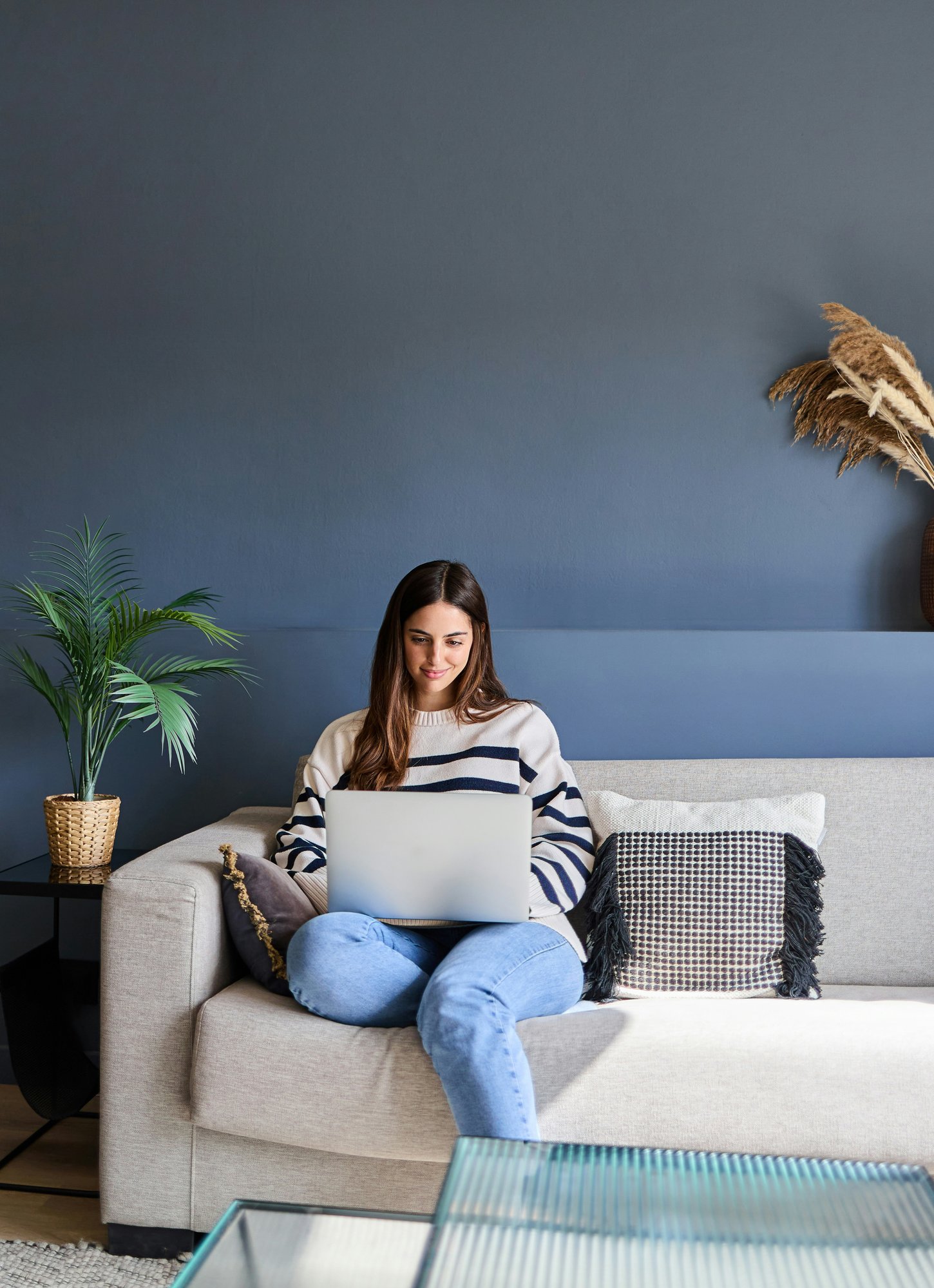 Woman working on a laptop on her living room couch
