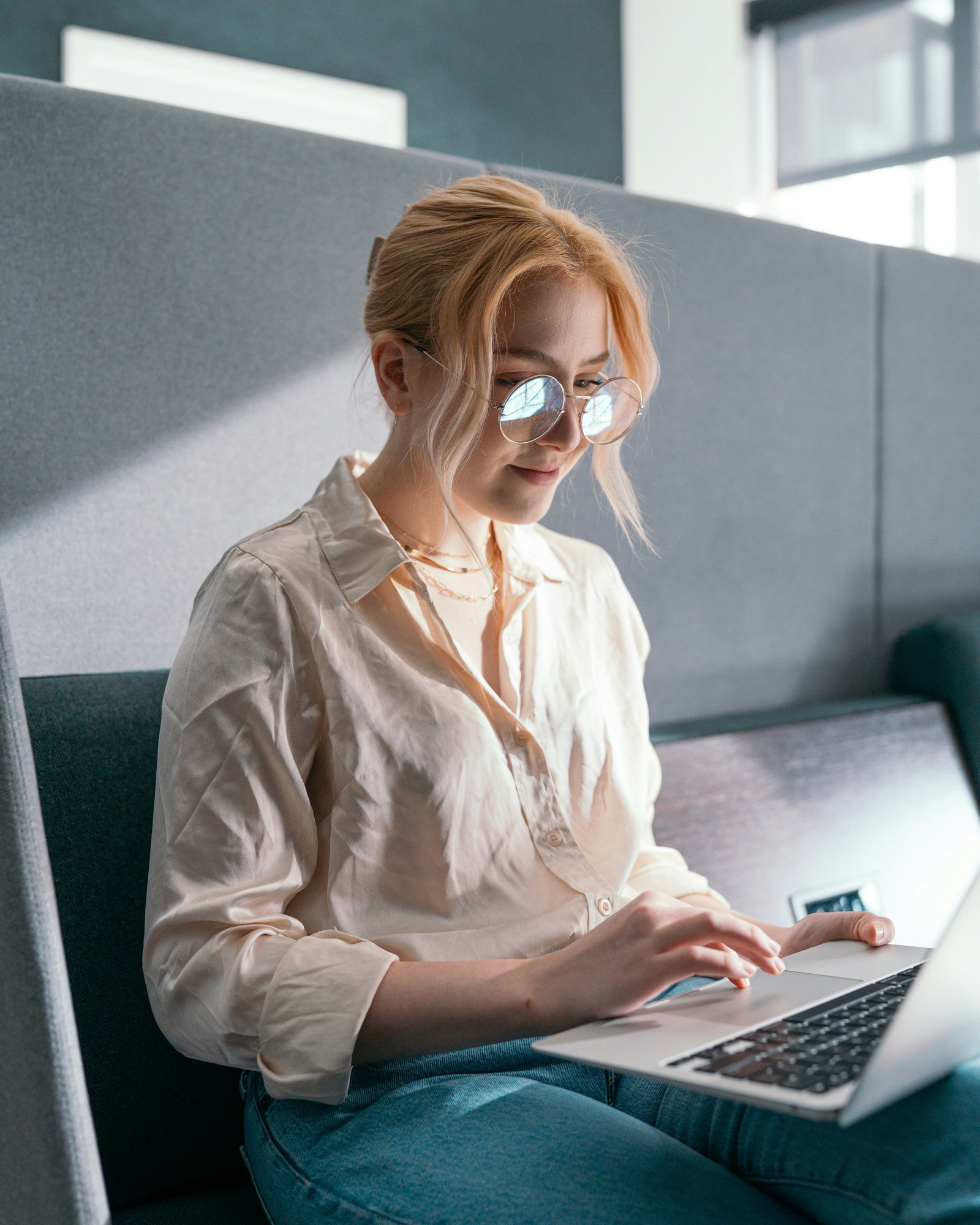 Woman in glasses typing on a laptop