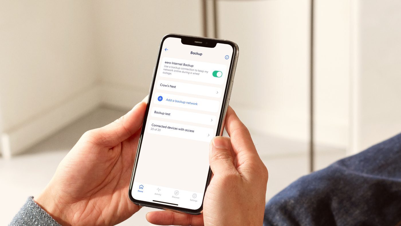 Hands holding a phone showing the eero app Internet Backup screen with backup turned on