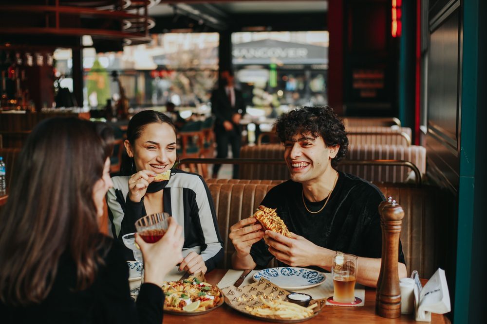 Friends laugh over burgers and fries in a restaurant booth