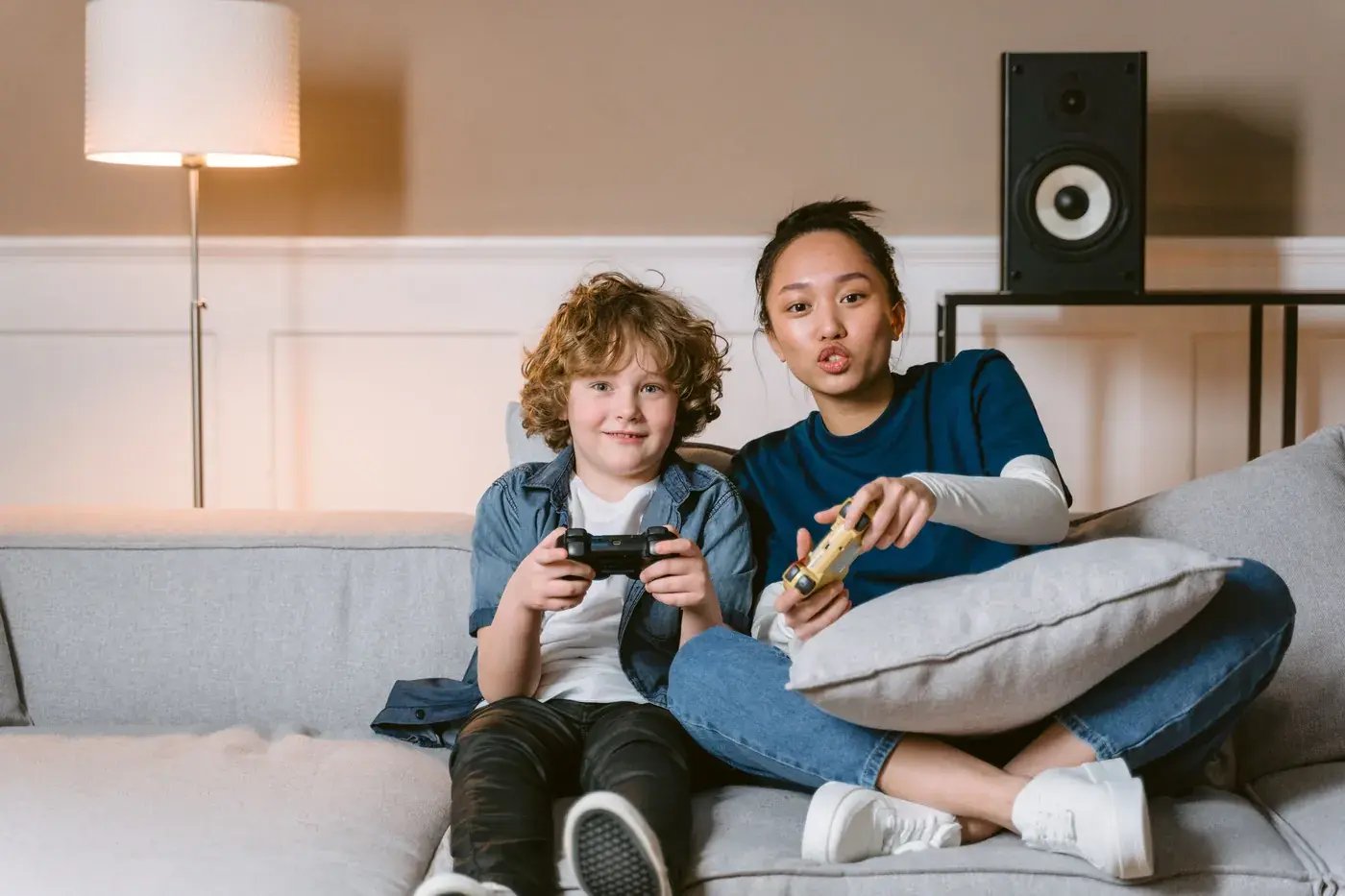 Young woman and boy playing video games on a sofa