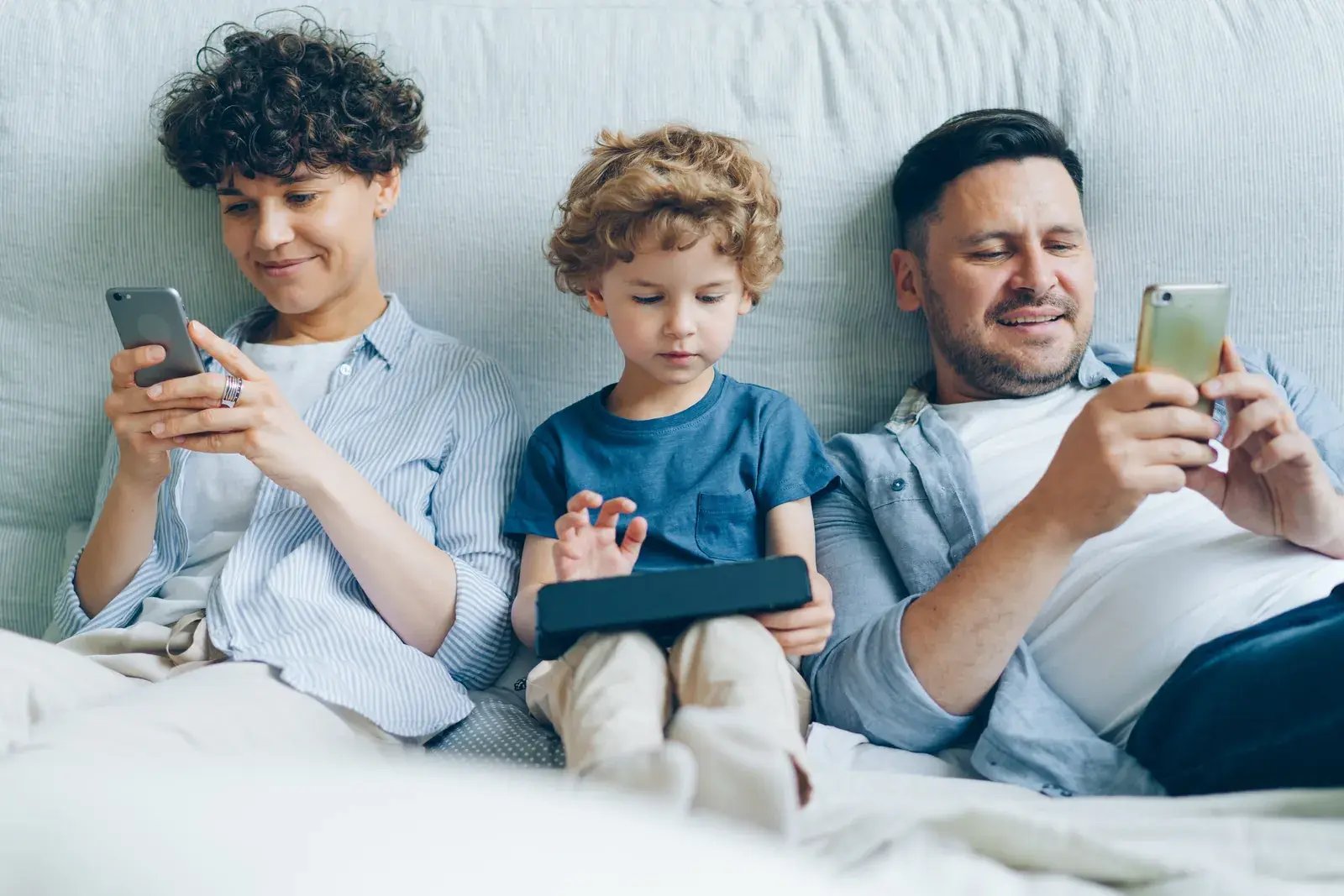 Family relaxing together on phones and a tablet