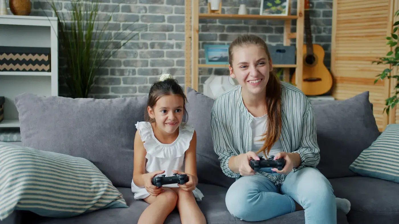 Mom and daughter laughing while playing a video game