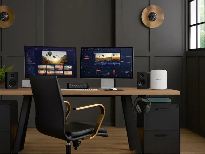 WiFi 7 eero router on a home office desk next to dual monitors