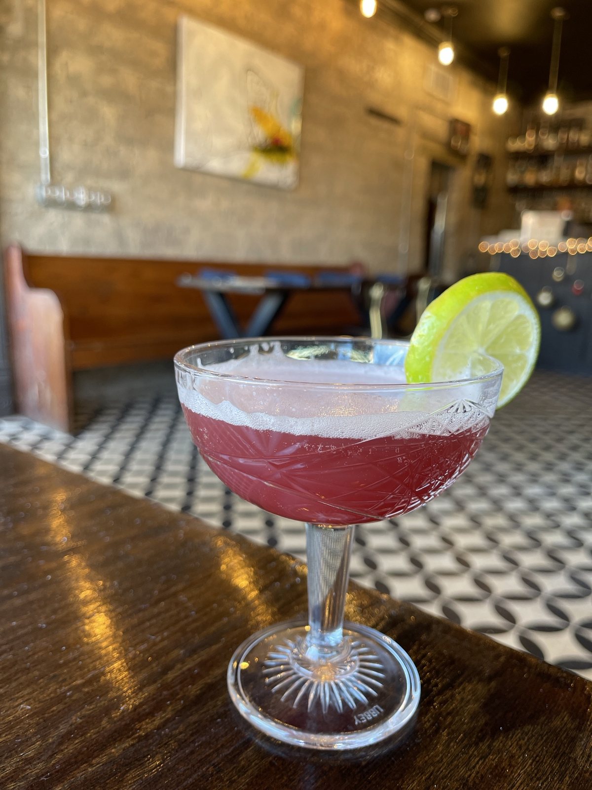 A rosy gimlet with a lime wheel on the bar at Theopolis Social Club